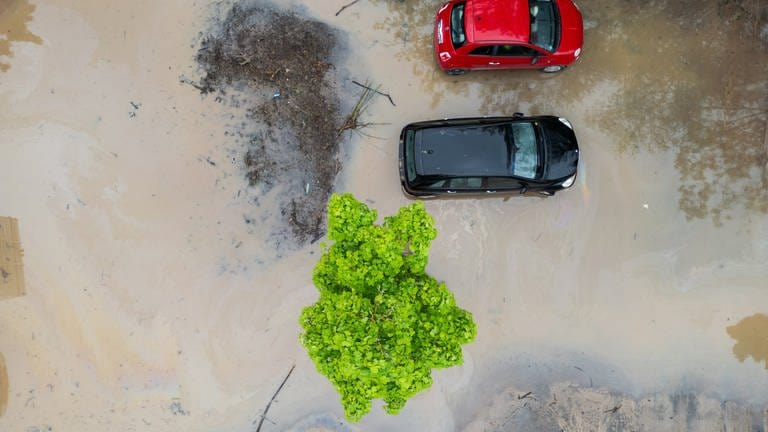 Samochody stoją na zalanym parkingu (widok z lotu ptaka z dronem).  W nocy ulewne deszcze spowodowały setki akcji gaśniczych i lokalne powodzie.