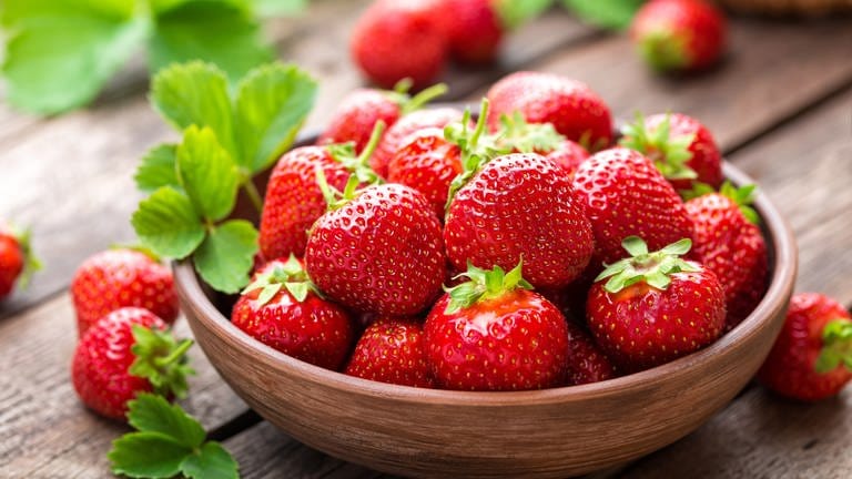 Eine Schale mit Erdbeeren steht auf dem Tisch. Erdbeeren sind gesund und schmecken besonders gut als Kuchen. Aber sie eignen sich auch für herzhafte Rezepte - zum Beispiel im Erdbeer-Spargel-Salat.  