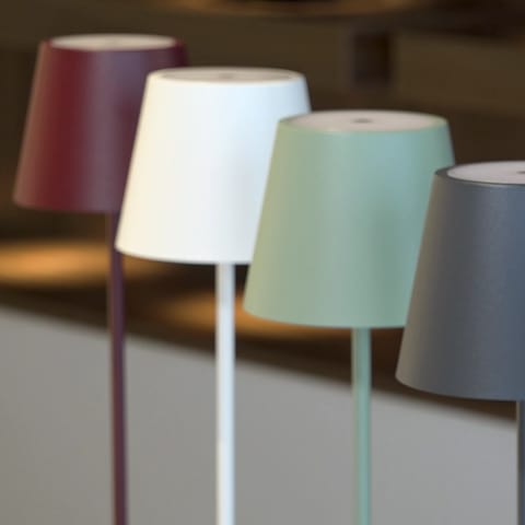 Bunte Lampen stehen nebeneinander. Wand- und Tischleuchten mit Akku – kabellos und praktisch. Wie lange halten die LED-Lampen? Und kann man die Akkus wechseln, wenn sie hinüber sind?  