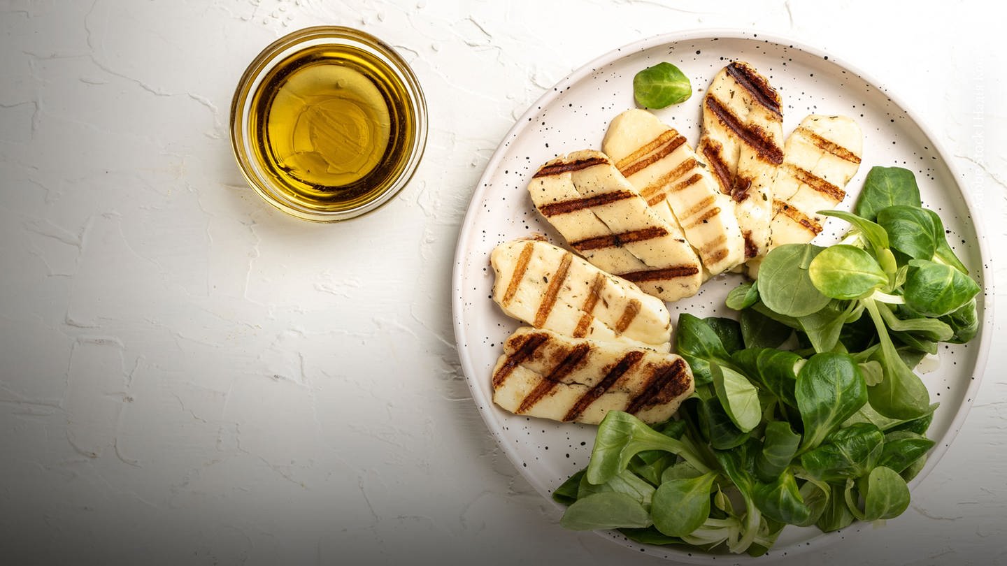 Auf einem Teller liegt Grillkäse mit Salat. Marktcheck testet zwei Halloumis und vier Grillkäse. Welcher schmeckt am besten? Und wie sieht es mit den Inhaltsstoffen bei der Laboranalyse aus? (Foto: Adobe Stock)