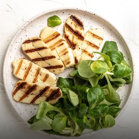 Auf einem Teller liegt Grillkäse mit Salat. Marktcheck testet zwei Halloumis und vier Grillkäse. Welcher schmeckt am besten? Und wie sieht es mit den Inhaltsstoffen bei der Laboranalyse aus? 