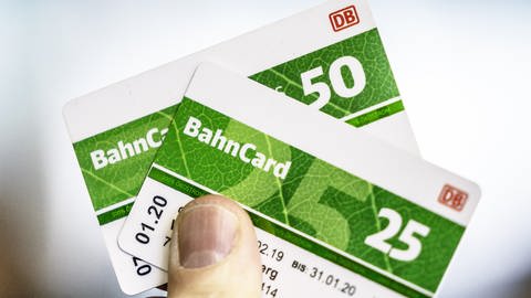 Ein Mann hält eine Bahncard 25 und eine Bahncard 50 in der Hand.