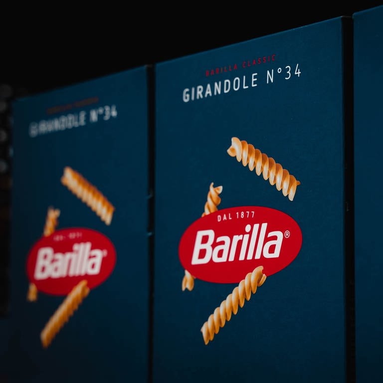 Blaue Nudelpackungen mit Rotem Barilla-Logo stehen in einem Regal. (Foto: Unsplash/ Paul Steuber)
