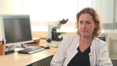 Gabriele Rapp, Dermatologin und Oberärztin am Klinikum Stuttgart sitzt an einem Schreibtisch, hinter ihr ein Computer und ein Mikroskop. (Foto: SWR)