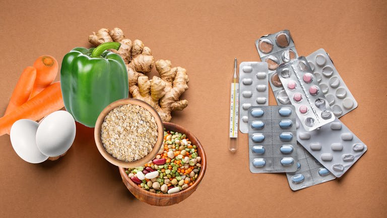 Gemüse wie Paprika, Karotten, Ingwer, Eier und Hülsenfrüchte auf der einen Seite und Medikamente z. B. Nahrungsergänzungsmittel auf der anderen Seite - was hilft, um das Immunsystem zu stärken? (Foto: Colourbox, AdobeStock)
