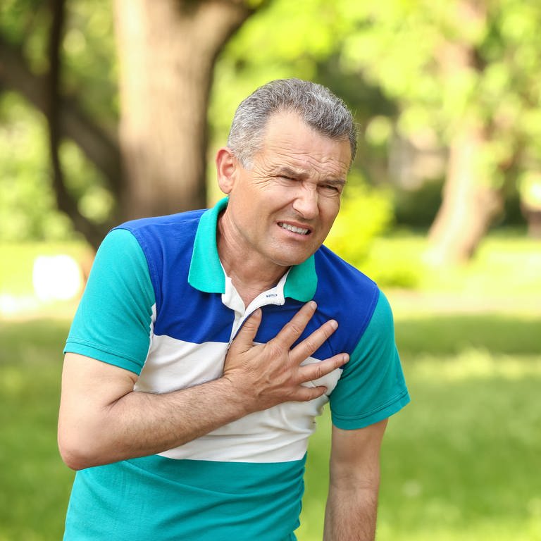 Ein älterer Mann greift sich mit schmerzverzerrtem Gesicht an den Brustkorb im Bereich des Herzens. (Foto: Adobe Stock)