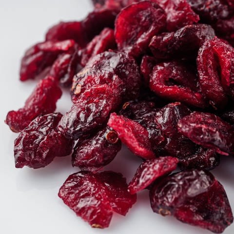 Getrocknete rote Cranberrys liegen auf einem weißen Tisch.