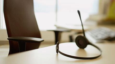 Ein leerer Schreibtisch, auf dem ein Headphone und eine Tastatur liegt. (Foto: Getty Images, Thinkstock -)