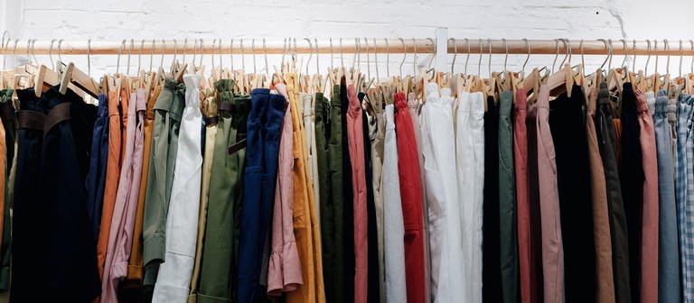 Kleidung an Kleiderstange - Woran erkennt man nachhaltige Kleidung? (Foto: Unsplash / Lucas Hoang)