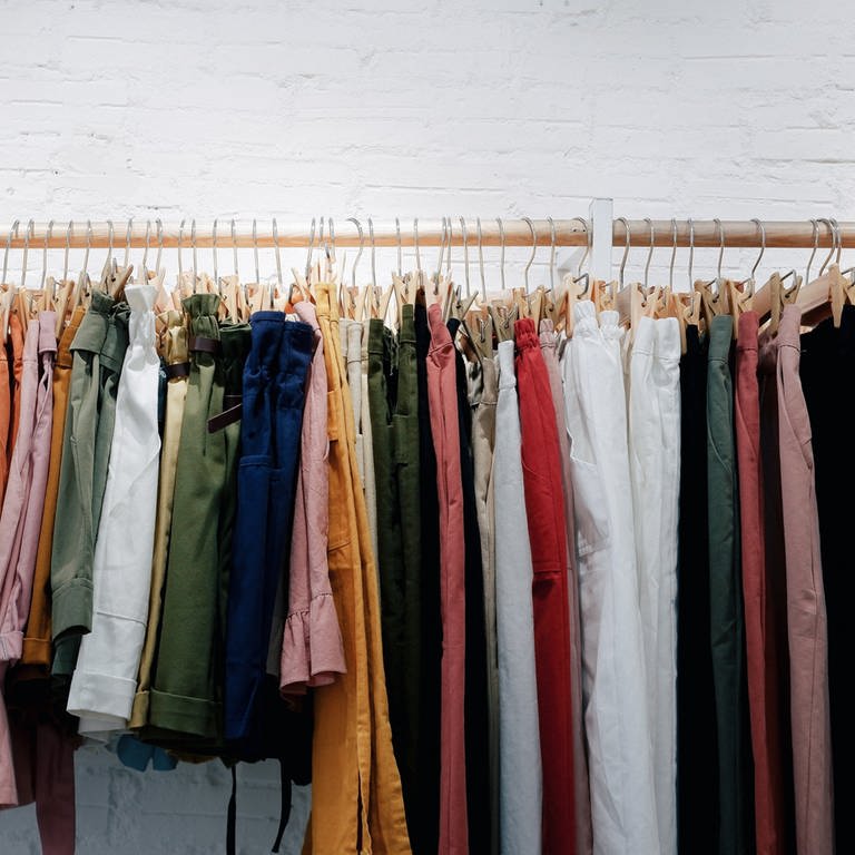 Kleidung an Kleiderstange - Woran erkennt man nachhaltige Kleidung? (Foto: Unsplash / Lucas Hoang)
