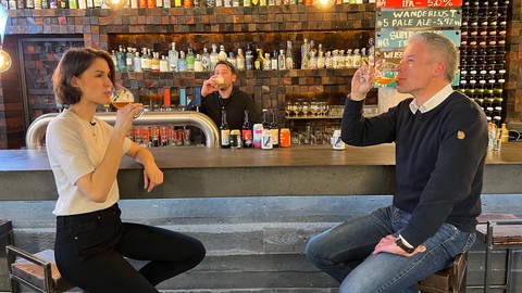 Ökochecker-Host Katharina Röben trinkt ein Bier an einer Bar. (Foto: SWR)