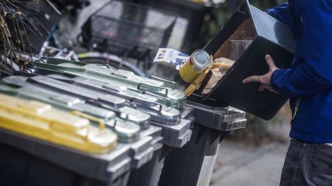 Ein junger Mann schüttet Abfall in eine Mülltonne. Je nach Wohnort bezahlen Haushalte in Deutschland nach einer Studie sehr unterschiedliche Müllgebühren. (Foto: dpa Bildfunk, picture alliance/dpa | Frank Rumpenhorst)