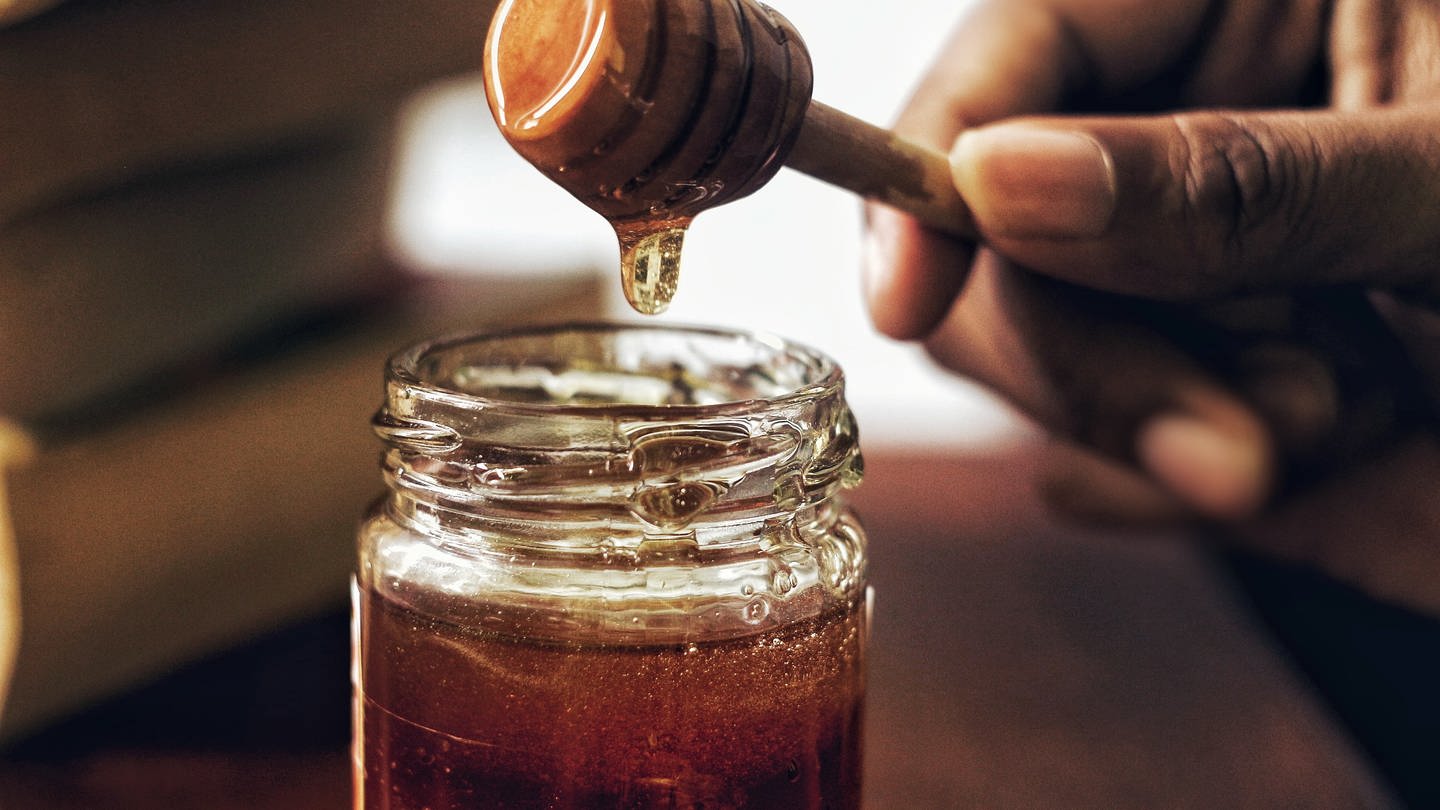 Honig wird mit einem Honiglöffel aus einem Honigglas genommen. Welcher Honig ist am besten?