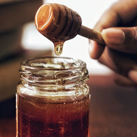Honig wird mit einem Honiglöffel aus einem Honigglas genommen. Welcher Honig ist am besten? (Foto: Unsplash / Arwin Neil Baichoo)