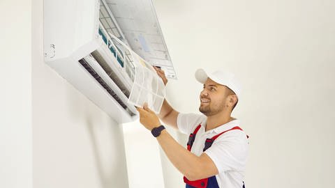 Ein Handwerker montiert eine Klimaanlage. Es handelt sich um ein Splitgerät, dass außen und innen angebracht werden muss. (Foto: Colourbox)