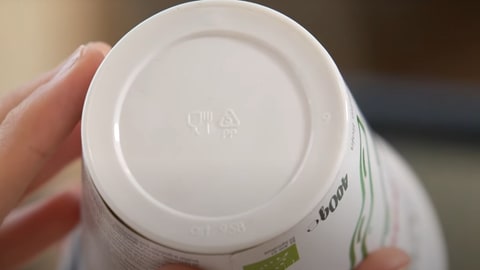 Weißer Joghurtbecher, der auf dem Boden die Zeichnung 'PP' trägt. Dies gibt an, dass der Becher aus dem Kunststoff Polypropylen hergestellt worden ist.
