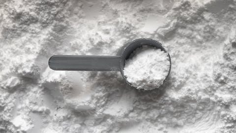 Sodium Laureth Sulfat: Weißes Pulver mit Löffel.