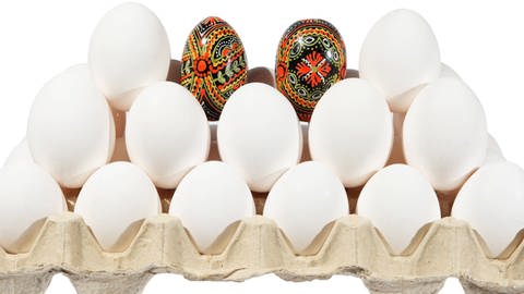 Weiße Eier in einer Eierpappe und ein farbiges Ei dazwischen  (Foto: IMAGO, Imago)