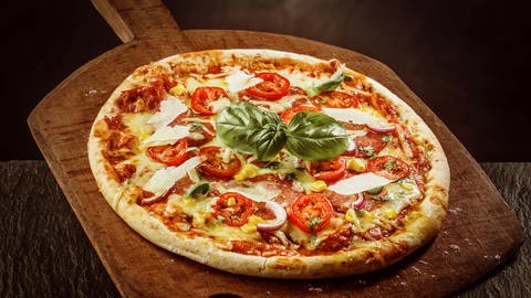 Pizza Margherita liegt auf einer großen Holzschaufel (Foto: IMAGO, Panthermedia)