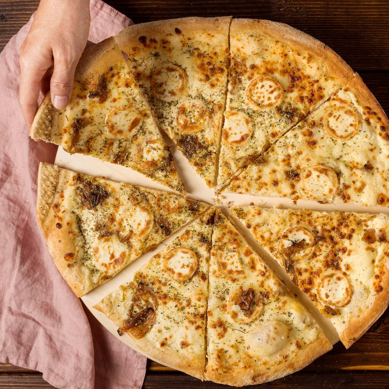zwei Hände nehmen je ein Stück von einer fertig gebackenen runden Pizza weg (Foto: IMAGO, imagebroker)