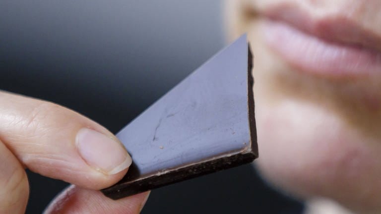 Eine Frau isst ein Stück dunkle Schokolade (Foto: IMAGO, photothek)