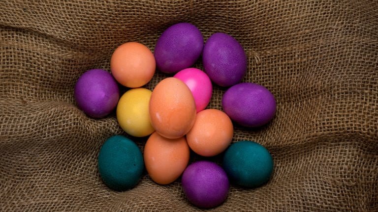 Mehrere bunte Eier liegen auf Sackleinen (Foto: IMAGO, Ulrich Roth)