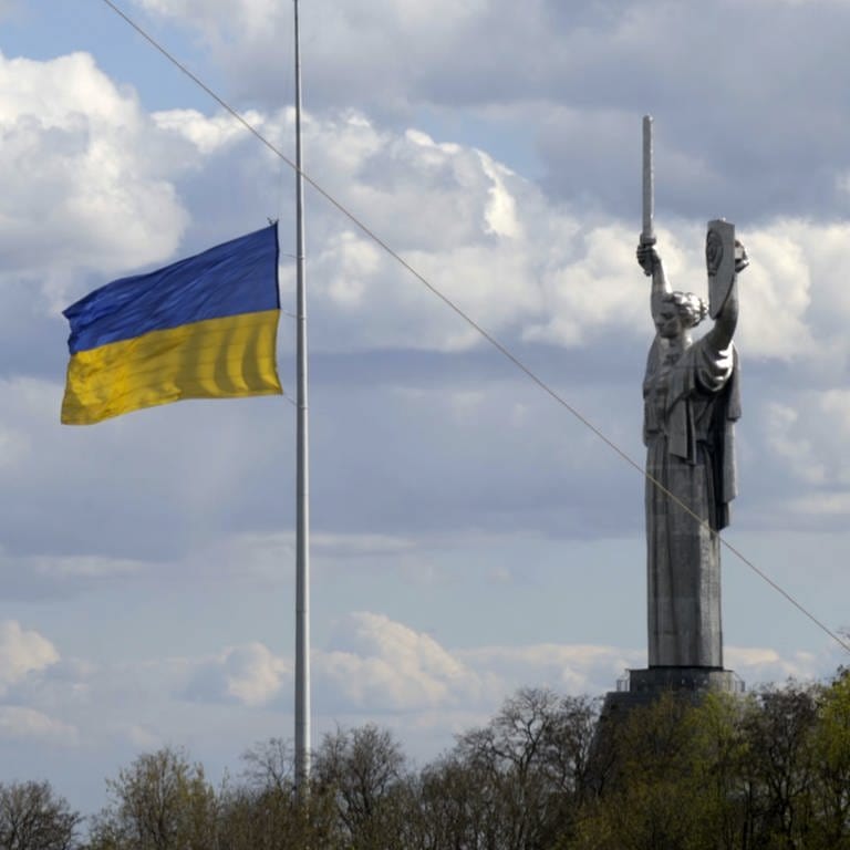 Aufnahme der Ukraine-Flagge an einem Fahnenmast neben der Mutter-Heimat-Statue in KyjiwKiew.