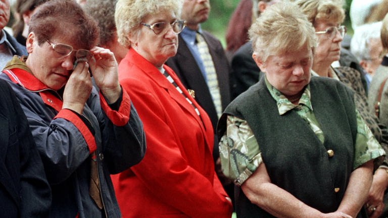 Mit den Tränen in den Augen stehen Angehörige am 28.08.1998 bei der Gedenkfeier anläßlich des zehnten Jahrestages der Flugzeugkatatrophe von Ramstein vor einer Gedenktafel. (Foto: SWR, picture alliance)