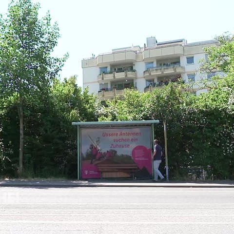 Telekom-Mitarbeiter an Bushaltestelle mit Plakat