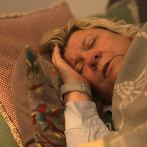 Frau liegt im Bett und hält sich den Kopf (Foto: SWR)