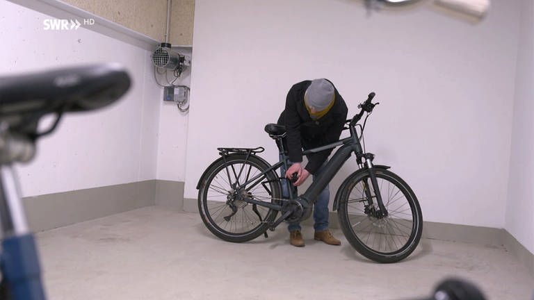 Mann öffnet Schloss seines Fahrrads (Foto: SWR)