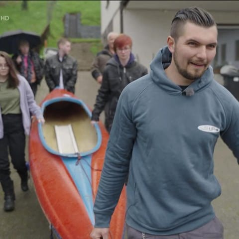 Theo Frisch und von ihm gerettete Menschen tragen ein Kanu (Foto: SWR)