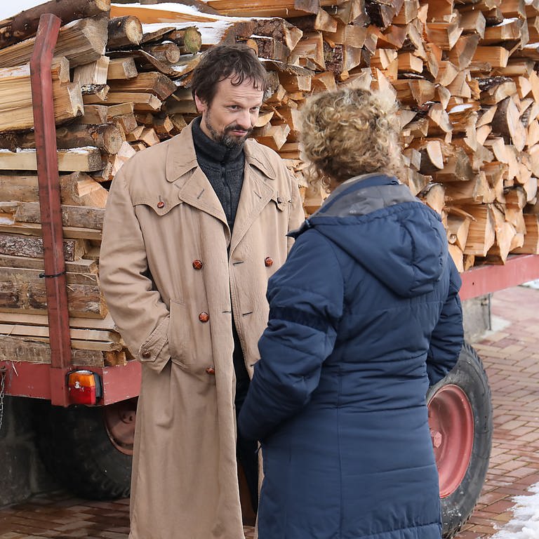 Bea und der neue Feriengast (Ron Spiess) hinterm Fallerhof vor einem Brennholzstapel