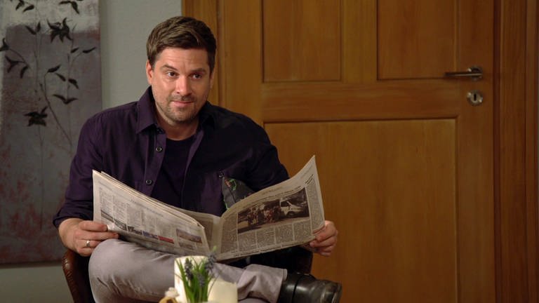 Andreas sitzt im Wohnzimmer und liest Zeitung. (Foto: SWR)