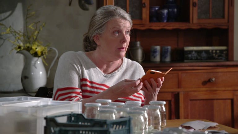 Evelyn Riedle sitzt mit ihrem Notizbuch am Fallerschen Küchentisch