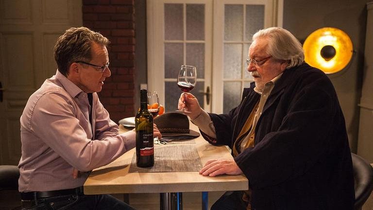 Bernhard und Hermann sitzen in Bernhards Wohnung bei einem Glas Rotwein zusammen