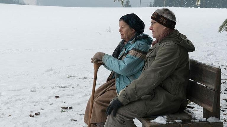 Lioba und Karl sitzen auf einer Bank im Schnee
