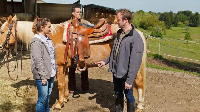 Jenny, Matthias, Bernd stehen bei einem Pferd vor dem Gestüt