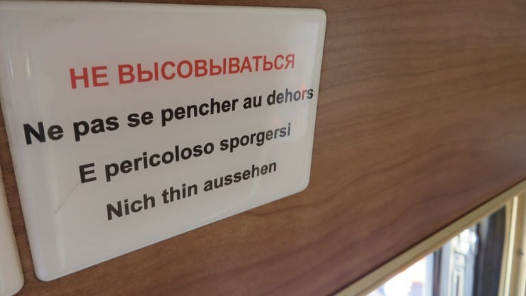 Ein Schild mit der Aufschrift:  Nicht hinauslehnen – lustig übersetzt in drei Sprachen