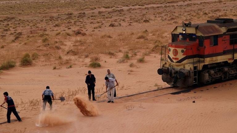 Sandverwehungen auf dem Gleis. Fleißige Helfer schaufeln dem Zug den Weg frei. - Die Sahara  bedeckt 9 Millionen  Quadratkilometer, knapp 20 % sind reine Sandwüste.