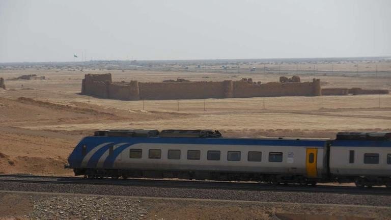 Schnellzug fährt mit Tempo 160 an der Karawanserei Mohammad Abad Kaj vorbei, Außentemperatur 50 Grad.
