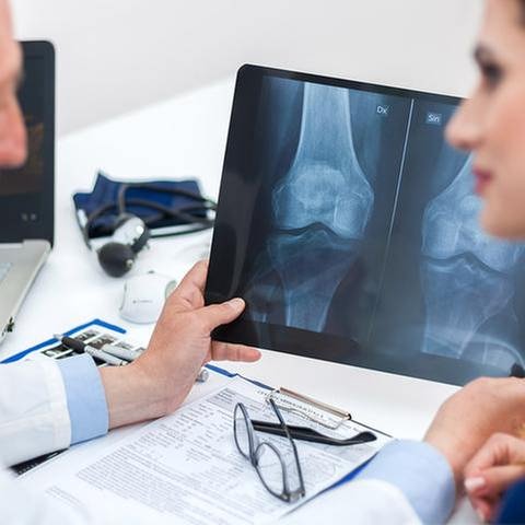 Eine Arzt erklärt einer Frau ein Röntgenbild.
