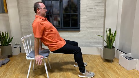 Fitness-Übung für Kopf und Nacken; Schultersenken auf einem Stuhl