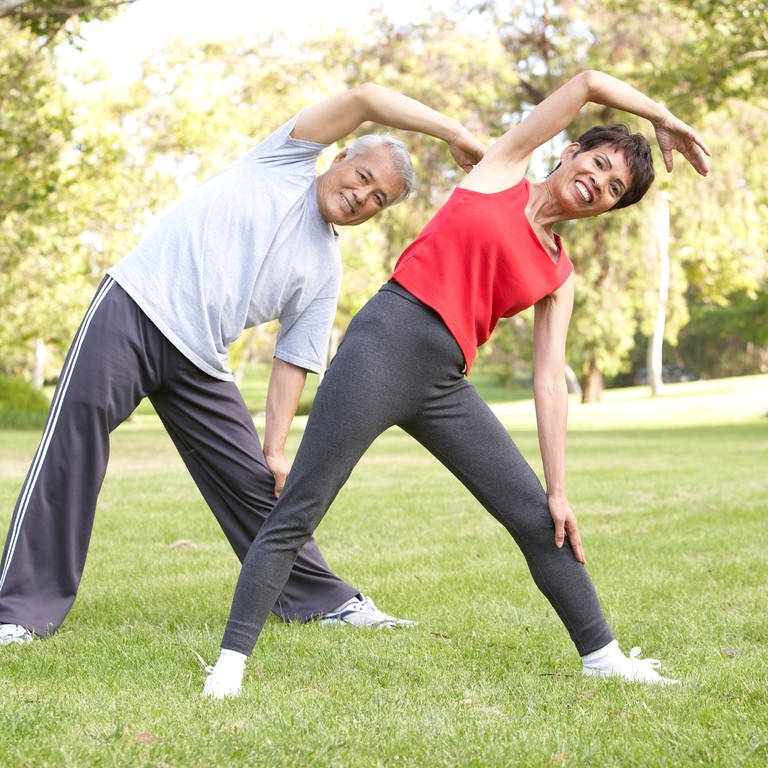 Gleichgewichtsübungen für mehr Fitness. Mann und Frau bewegen sich im Park