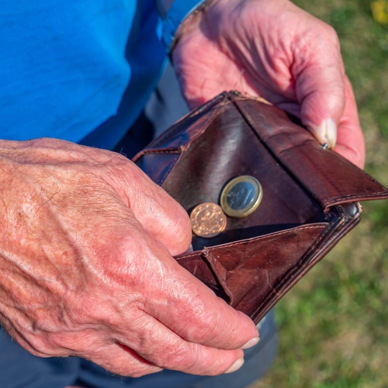 Ein alter Mann kramt in einem Geldbeutel mit wenigen Münzen. Für viele Rentenbezieher stellen steuerliche Abzüge eine finanzielle Bedrohung dar. 