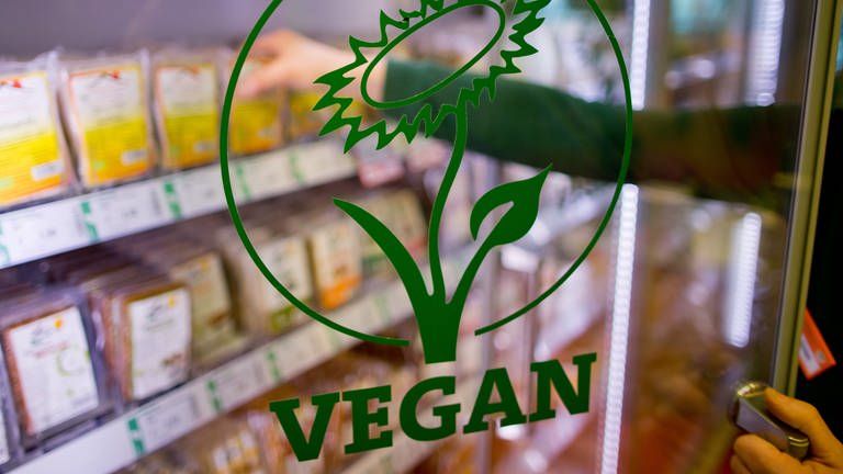  Das Wort "Vegan" ist auf der Glastür eines Kühlregals mit veganen Produkten in einem Biosupermarkt zu lesen. Ersatprodukte für Fisch oder Visch gibt es immer mehr.
