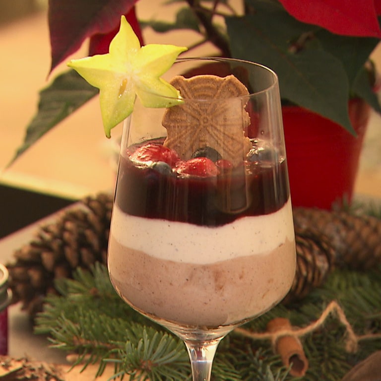 Ein Nachtisch ist in einem Weinglas angerichtet. Im Hintergrund ist weihnachtliche Dekoration.