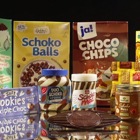Verschiedene Schoko- und Choc-Produkte stehen vor schwarzem Hintergrund. Ist da Schokolade drin oder billige Ersatzstoffe?