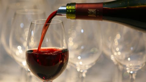 Rotwein wird in ein Weinglas gefüllt.