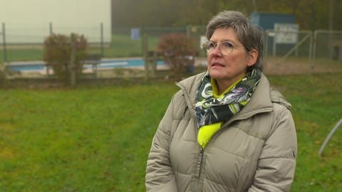 Claudia Zobel vom Kneipp-Bund Saarland steht auf einer Wiese, hinter ihr ist ein Kneippbecken zu sehen.